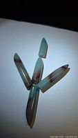 Four elongated bullet-cut aquaprase gemstones arranged in a Y formation