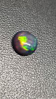 Front view of round black opal cabochon showing play of color