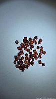 Group of square orange-red garnets scattered on white background