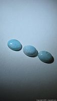 Three oval Larimar cabochons on neutral background