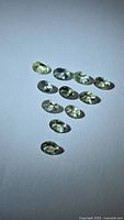 Group of 10 oval faceted yellow-green tanzanite gemstones on neutral background