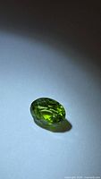 Front angled view of oval green Peridot on neutral background