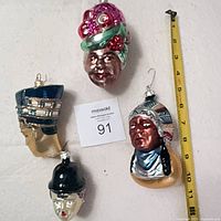 Four glass head ornaments laid near tape measure