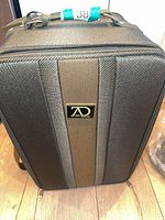 Front of hard-sided carrying case showing exterior design and logo