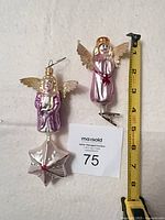 Front view of both Radko glass angel ornaments beside measuring tape