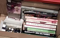 Overview of hairpiece packaging, box of nail products and row of books in cardboard box