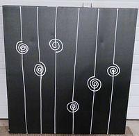 Front view of abstract black canvas with white lines and spirals