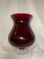 Front view of ruby red hurricane vase on white backdrop