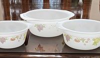 Front view of three Indopal milk glass casserole bowls showing fruit pattern and sizes