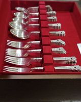 Forks and spoons arranged in red-lined drawer of wooden case