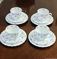 Four cup, saucer and plate trios displayed