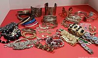entire assortment of bracelets and bangles laid out on red surface
