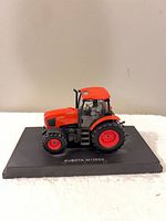 Left side view of die-cast Kubota M135GX tractor on base