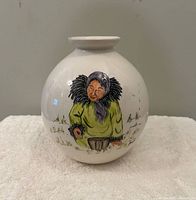 Front view of spherical white ceramic vase with painted Inuit figure and artist signature
