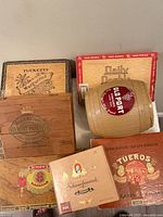 Group shot of seven vintage cigar boxes and barrel container