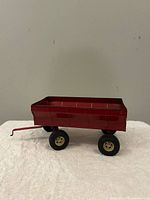 Left side view of red Ertl hay wagon showing hitch and wheels