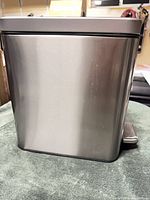 Side view of stainless steel trash can showing rectangular shape and pedal