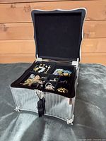 Open mirrored jewelry box showing interior compartments and contents