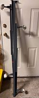 Folded metal bed frame leaning against door showing overall length and wheels