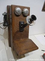 Three-quarter side view showing oak case, bells, mouthpiece, receiver, shelf