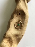 Front view of circular gold pendant with emerald