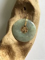 Front view of jade disc pendant on driftwood display