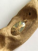 Front view of pendant showing jade cabochon and gold crane motif