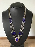 Full view of multi-strand sterling liquid silver necklace with lapis beads and oval pendant on display bust