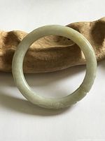 Full view of pale green jade bangle on wooden prop