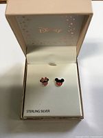 Open Disney box showing Minnie and Mickey sterling silver enamel stud earrings on card