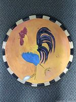 Full view of circular wooden plaque showing rooster painting and rim