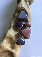 Front view of pendant on driftwood prop showing five coloured hearts