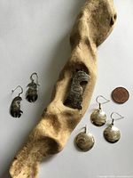 Front view of all jewelry pieces on driftwood with coin for scale