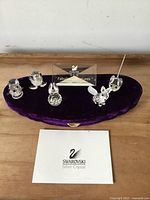 Overall view: five crystal animals on purple velvet base with plaque and booklet
