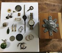 Overall group of jewelry, watches, key, coin and box on display board