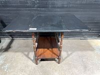 Front view of the drop-leaf table showing painted top and turned legs