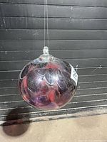 Full view of blown glass orb hanging by line