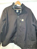 Front view of black Carhartt soft shell coat on hanger