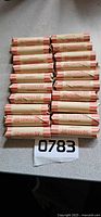 Twenty rolled penny wrappers arranged in four rows on countertop with lot number card
