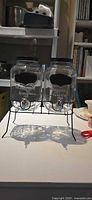 Front view of two glass dispensers on black metal stand