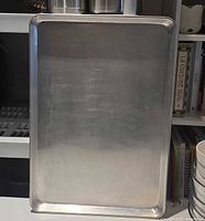 Single aluminum baking sheet upright showing surface and rim