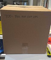 Closed cardboard box labeled "700- 8oz hot cup lids"