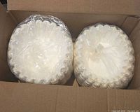 Open carton showing two stacks of unused white paper coffee filters wrapped in plastic