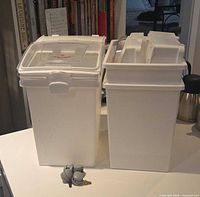 Two lidded containers side by side with loose caster wheels visible