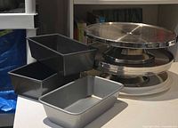Stacked stainless cake stands, plastic cake plate and three loaf pans