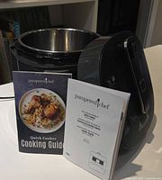 Quick Cooker open with stainless pot and two Pampered Chef booklets