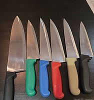 All six knives laid out showing blade shapes and handle colours