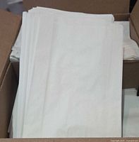 Stack of white paper sandwich bags inside open cardboard box