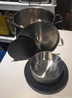Stainless stock pot, noodle sieve inside, insulated serving bowl with base and lids arranged