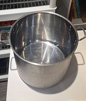 Large stainless steel stock pot, interior and handles visible